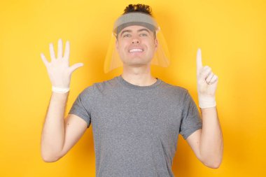 Adam kendini beğenmiş ve mutlu bir şekilde gülümserken altı numarayı işaret ediyor..