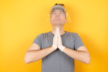 Plastik şapkalı bir adam, elleri bağlı yalvarıyor ve dua ediyor. Yüzünde umut ifadesi var. Çok duygusal ve endişeli. Soruyorum.