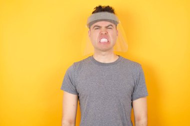 İzole edilmiş sarı arka plan üzerinde duran kızgın beyaz adam portresi, dişlerini sıkar, tatminsizlik içinde kaşlarını çatar, görevleri yüzünden tedirgin olur. Öfkeli adam.  