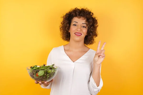 波伊图尔的女人拿着碗里的沙拉 用第二根手指显示和指出来 同时带着自信和快乐的笑容 — 图库照片