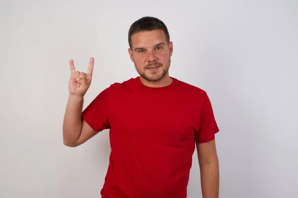 Young Caucasian Man Doing Rock Gesture Smiling Camera Wearing Red — Stock Photo, Image