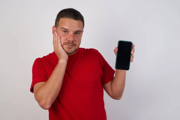 一个手牵着脸展示手机屏幕的男人 — 图库照片