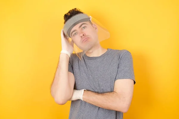 Plastik Şapkalı Çok Sıkılmış Bir Adam Sarı Arka Planda Poz — Stok fotoğraf