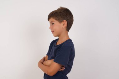 Neşeli, sevimli, sıradan tişörtler giyen güzel çocuk izole beyaz arka planda duruyor, kollarını kavuşturup, güzel bir sohbet yapıyor.