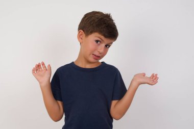 Ayrı beyaz arka planda duran, omuz silken, kuşkulu yüzler, avuçlarını ayıran, zor bir karar veren, cahil, güzel çocuk tişörtünü giyiyor.