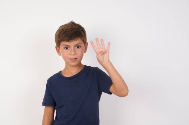 Güzel çocuk, izole edilmiş beyaz arka planda duran sıradan bir tişört giyiyordu. Dört numaralı parmaklarını gösteriyordu ve gülümsüyordu. Kendinden emin ve mutluydu..