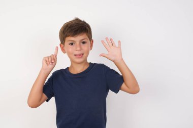 Beyaz stüdyodaki beyaz çocuk, altı numarayı parmaklarıyla gösteriyor. 