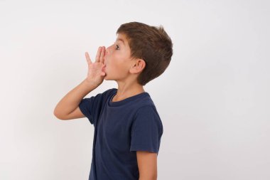 Beautiful kid boy wearing casual t-shirt standing over isolated white background, shouting and screaming loud to side with hand on mouth. Communication concept. clipart