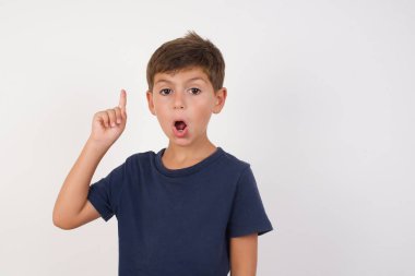 Güzel çocuk, izole edilmiş beyaz arka plan üzerinde sıradan tişörtler giyerek başarılı bir fikir sunuyor. Heyecanlı ve mutlu. Bir numara..