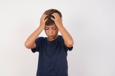 Güzel çocuk, izole edilmiş beyaz arka plan üzerinde duran günlük tişört giyiyor. Aşırı çalışma yüzünden baş ağrısı ve stresten acı çekiyor. Depresyon ve acı kavramı.