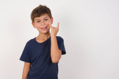 Güzel çocuk, izole edilmiş beyaz arka planda dikilip kameraya gülümseyen sıradan bir tişört giyiyor. Beyaz duvara karşı duran kırmızı gömlekli. En sevdiği konsere gitmeye hazır..