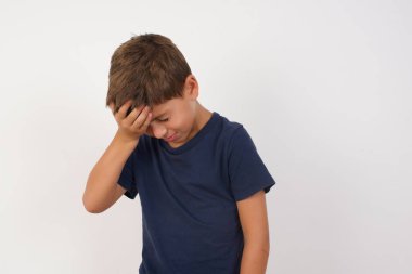 Çok üzgün ve yalnız bir çocuk. Günlük tişörtler giyen güzel bir çocuk. İzole edilmiş beyaz arka planda duruyor, ağlıyor., 