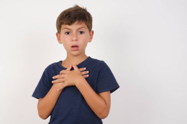 Korkak güzel çocuk, izole edilmiş beyaz arka plan üzerinde duran, korkmuş bir ifadeyle duran, ellerini göğsünde tutan, garip bir şeyi fark etmek için şaşıran, güzel çocuk, sessiz tepki ve duygular..
