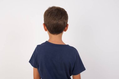 İzole edilmiş beyaz arka planda duran günlük tişörtler giyen güzel bir çocuğun arka görüntüsü. Stüdyo Çekimi.