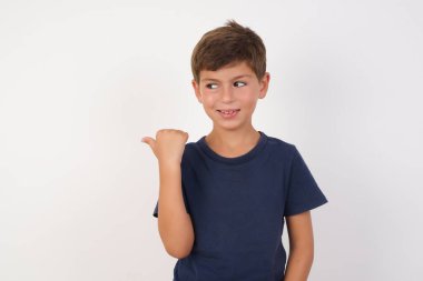 İzole edilmiş beyaz arka plan üzerinde duran günlük tişört giyen güzel çocuk, fotokopi alanına bakan tanıtımcı, reklamlar... 