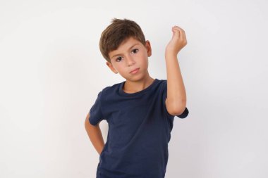 İzole edilmiş beyaz arka plan üzerinde duran sıradan tişört giyen güzel çocuk tipik İtalyan jestleri yapıyor, kameraya bakıyor.