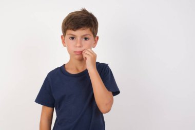 Güzel çocuk, izole edilmiş beyaz arka plan üzerinde sıradan bir tişört giyer ağzı ve dudakları parmaklarıyla fermuar gibi kapalıdır. Gizli ve sessiz, tabu konuşması.