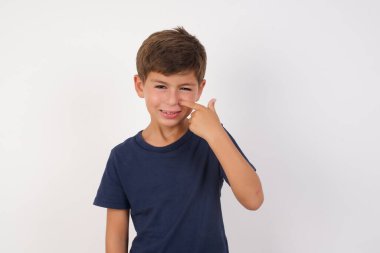 İzole edilmiş beyaz arka plan üzerinde duran sıradan tişört giyen güzel çocuk alnındaki sivilceden mutsuz olduğunu gösteriyor. Siyah noktalı çirkin bir enfeksiyon. Sivilce ve deri problemi