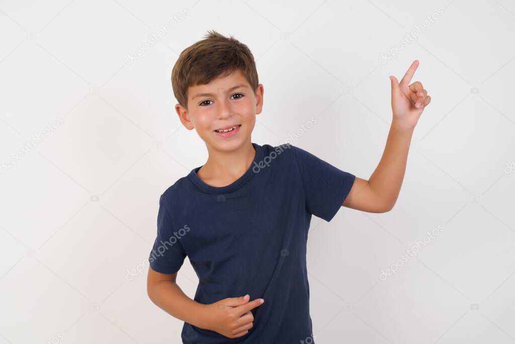 Beautiful kid boy wearing casual t-shirt standing over isolated white background,indicating finger empty space sales manager