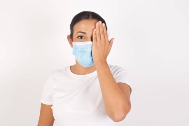 Sarıya boyanmış kırmızı tişörtlü yakışıklı adam bir gözünü eliyle kapatıyor, yüzünde kendine güvenen bir gülümseme ve sürpriz bir duygu var..