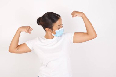 Kıvırcık saçlı, kırmızı tişörtlü, gururla gülümseyen kollarını gösteren yakışıklı beyaz bir adam. Fitness konsepti.