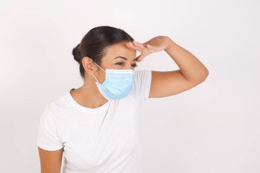 İzole edilmiş beyaz arka planda duran tıbbi maske takan genç bir Arap kadın çok mutlu ve gülümsüyor. Konsept aranıyor.