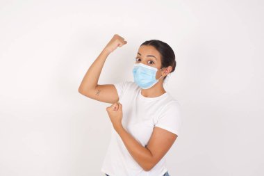 Medikal maske takan heyecanlı genç Arap kadının profil fotoğrafı izole edilmiş beyaz arka planda duruyor. Kara Cuma alışverişini kutlayan yumruklar havada uçuşuyor. 