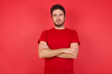 Ciddi yüzlü, çapraz kollu bir adam kameraya bakıyor. Pozitif kişi