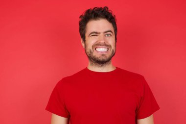 Cilveli adam, mutlu bir şekilde gülümsüyor, kameraya neşeli bir şekilde göz kırpıyor, flört ediyor. 