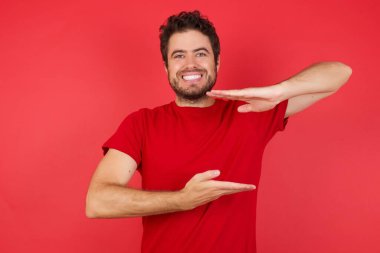 Büyük ve büyük boyut işareti, ölçü sembolü gösteren el kol hareketi yapan bir adam. Kameraya bakıp gülümsüyor. Ölçüm konsepti.