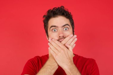 Kırmızı arka plan, stüdyoda elleri titreyen bir adam ağzı ve elleri yanlışlıkla kapatmak, gizli konsept. 