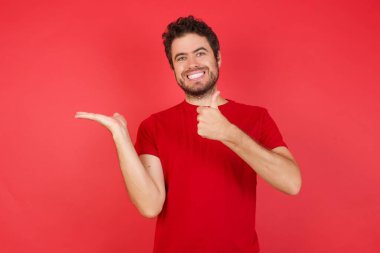 Adam elini gösteriyor ve baş parmaklarıyla iyi bir hareket yapıyor, mutlu ve neşeli gülümsüyor.