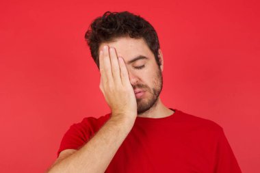 Kırmızı stüdyodaki mutsuz adam, el pençe divan duruyor. 