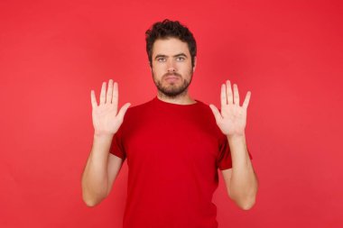 Ciddi yakışıklı adam elleriyle jesti durduruyor. 