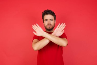 Kırmızı tişörtlü adamın reddedilme ifadesi var. Kollarını kavuşturuyor, avuç içleri negatif işaretler veriyor, kızgın yüz ifadesi var..