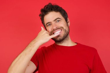 Genç, yakışıklı bir adam telefonla konuşurken gülümseyerek el ve parmaklarıyla hareket ediyor. İletişim kurma 