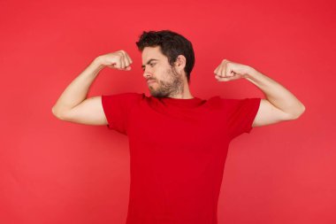 güçlü, mutlu adam kırmızı stüdyoda heyecanlı, kazanan adam kaslarını gösteriyor. 