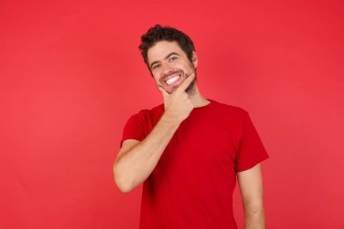 Kırmızı arka plan, stüdyoda kendine güvenen bir adam, kameraya bakıyor kollarını kavuşturmuş ve çenesini kaldırmış gülümsüyor. Olumlu düşünüyorum..