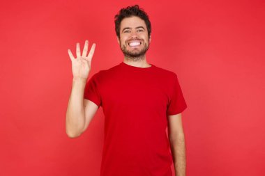 Adam kendini beğenmiş ve mutlu bir şekilde gülümserken dört numarayı işaret ediyor..