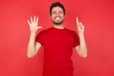 Adam parmaklarıyla altı numara gösteriyor ve kamerada gülümsüyor.