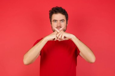 Kırmızı stüdyodaki mutsuz adam, parmaklarıyla dur hareketi yapıyor. 