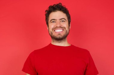 İyimser, mutlu adam kırmızı stüdyoda heyecanlı, kazanan kameraya bakıyor.