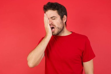 Yarı yüzü, gözü ve ağzı eliyle kapatan esnemiş adam.