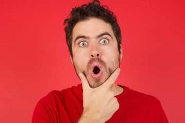 Şok olmuş bir adam, inançsızlıktan, şaşkınlıktan ve elleri çenesinde şaşkınlıktan büyülenmiş bir şekilde bakıyor.