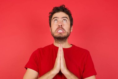 Kafkasyalı genç bir adam elleriyle yalvarıyor ve dua ediyor. Yüzünde umut ifadesi var. Çok duygusal ve endişeli. Soruyorum.