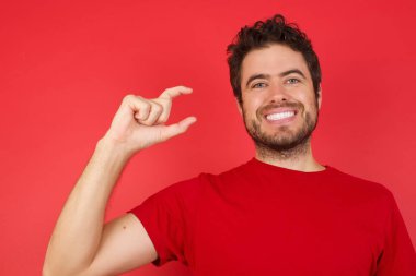 Elinde el hareketleriyle gülümseyen, parmaklarıyla işaret eden ve kameraya bakan bir adam. Ölçü kavramı