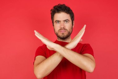 Kırmızı stüdyoda mutsuz bir adam, elleriyle jesti durduruyor. 
