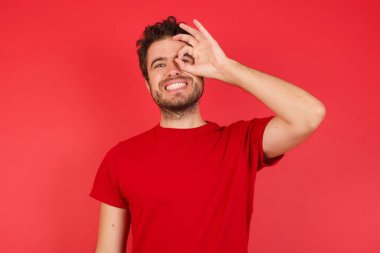 Adam iyi bir jest yapıyor. Gülümsüyor. Gözleri mutlu yüzle parmaklarının arasından bakıyor..