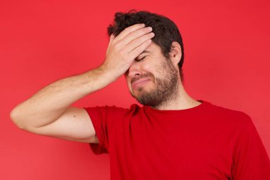 Çok üzgün ve yalnız genç yakışıklı beyaz bir adam izole edilmiş kırmızı arka planda tişört giyiyor. Ağlıyor, 