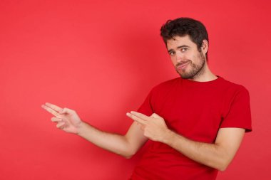 Bağıran genç yakışıklı beyaz adam izole edilmiş kırmızı arka plan üzerinde tişört giyiyordu. Yarışmalar kazanmıştı. Satış indirimli malları hayretler içinde görmüştü. 